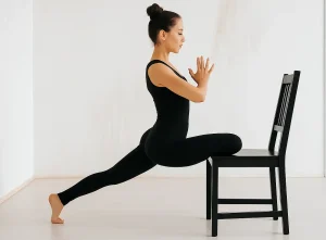 Woman doing yoga lunge pose with chair indoors