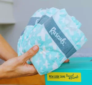 Hand holding Rascal and Friends Diaper packs from a new box