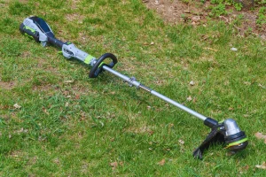 Battery-powered string trimmer placed on green lawn