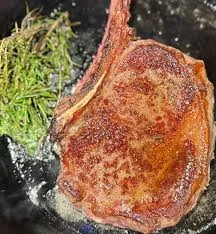 Best Steak Delivery showcasing seared ribeye with herbs in skillet