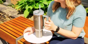 Woman holding stainless Target Stanley Cup outdoors.