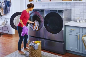 Woman loading laundry into front load washers with agitators.