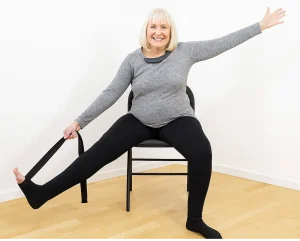 Senior woman stretching with strap on chair