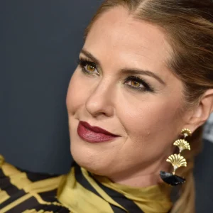 Leslie Grossman in gold outfit and earrings