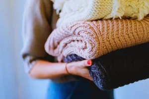 Poplin Laundry customer holding folded knitted sweaters