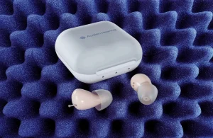 Audien Atom hearing aids with charging case on blue foam