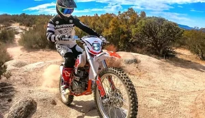Rider on a Kayo dirt bike navigating rocky off-road 