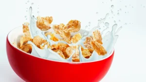 All Cereals splashing in milk inside a red bowl.