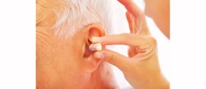 Audien Atom hearing aid being inserted into elderly man's ear