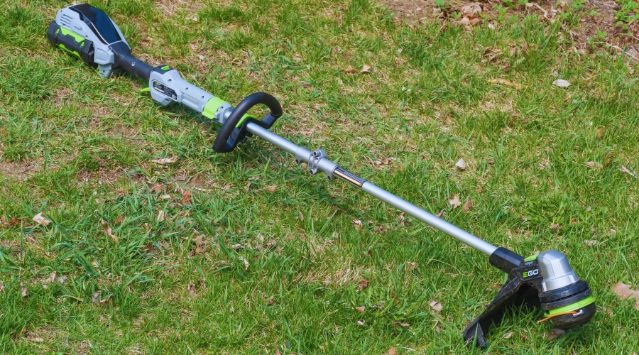 Battery-powered string trimmer placed on green lawn